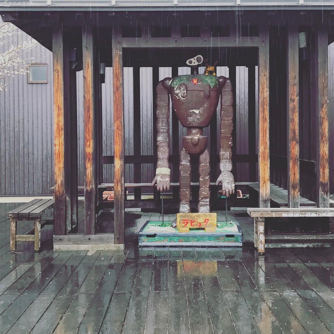 木の小屋に立つ、さびたロボットの像