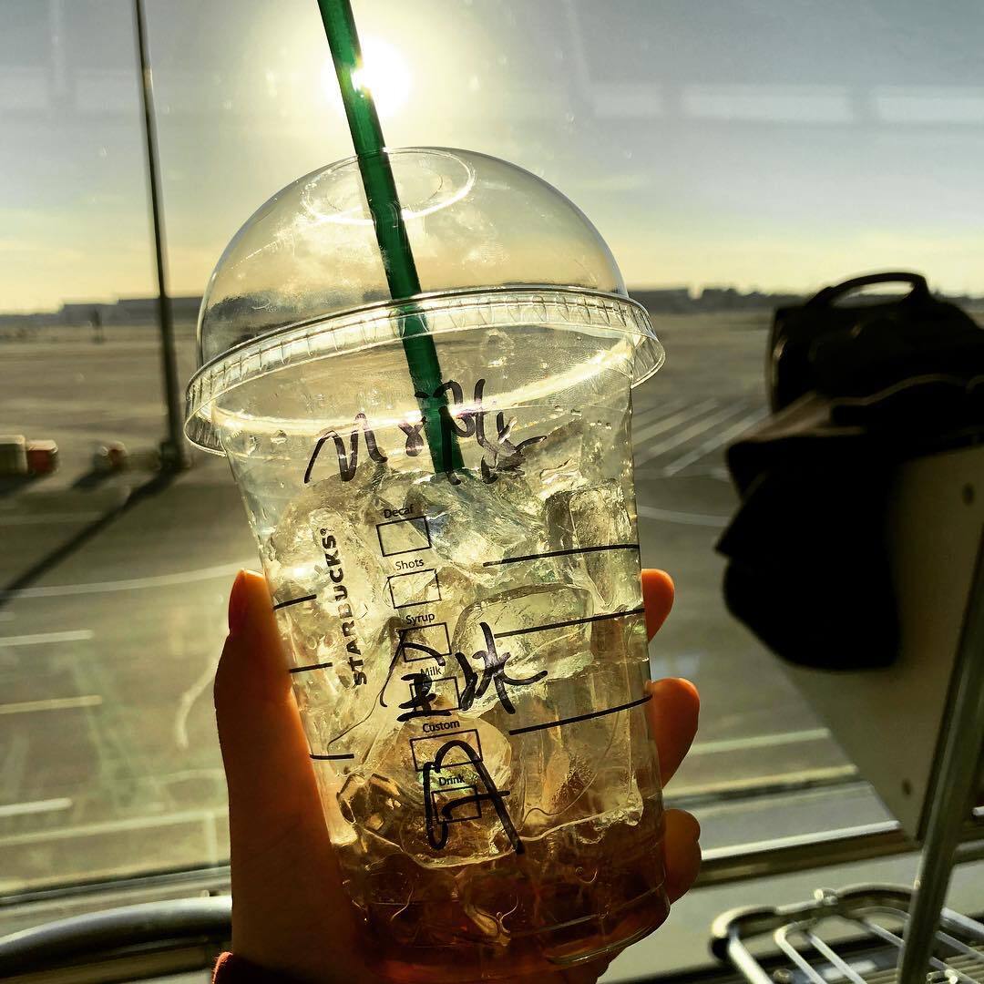 空港の窓ぎわで持つ、飲みかけのアイスドリンク