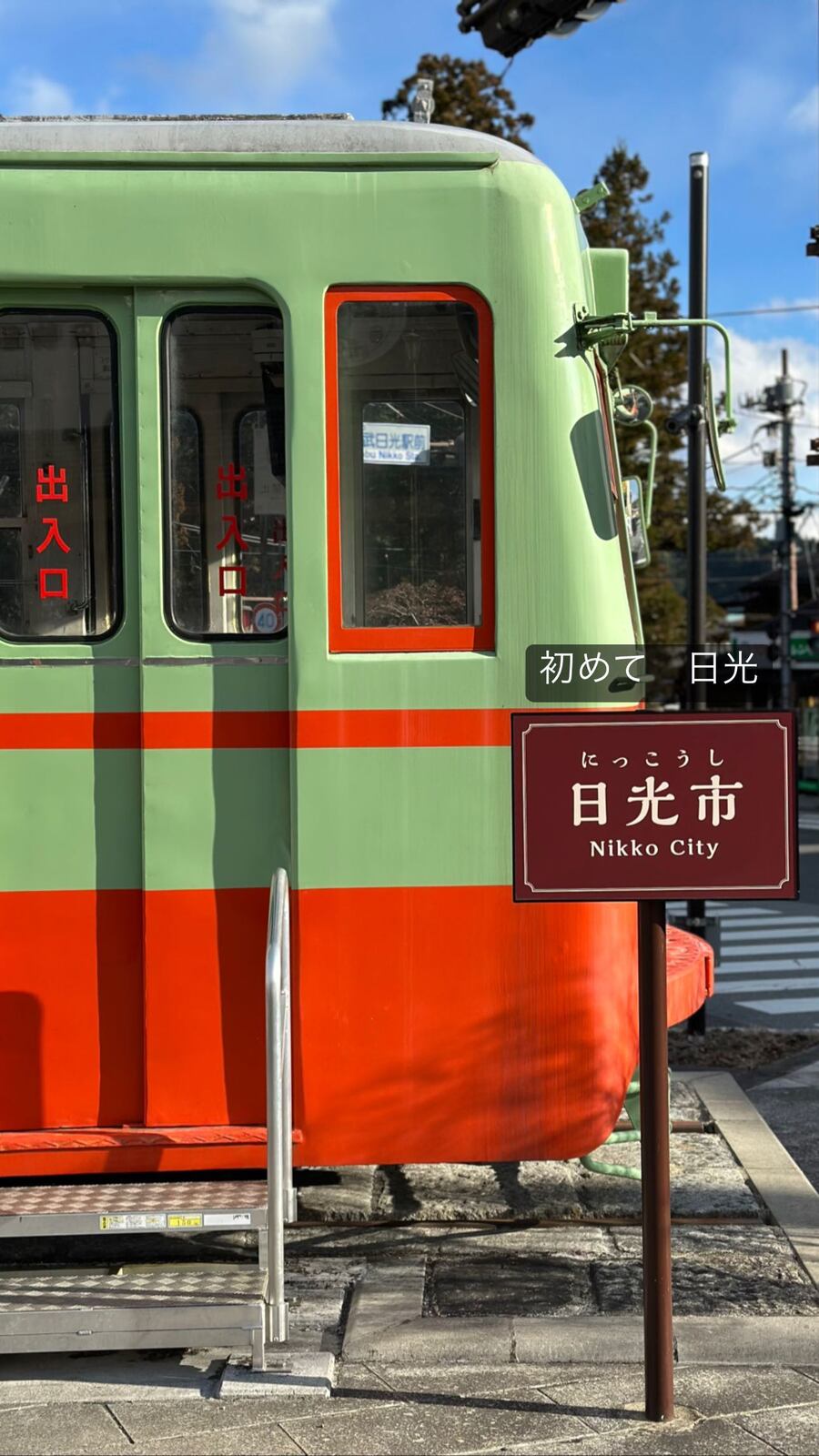 緑と赤の古い電車と「日光市」の看板