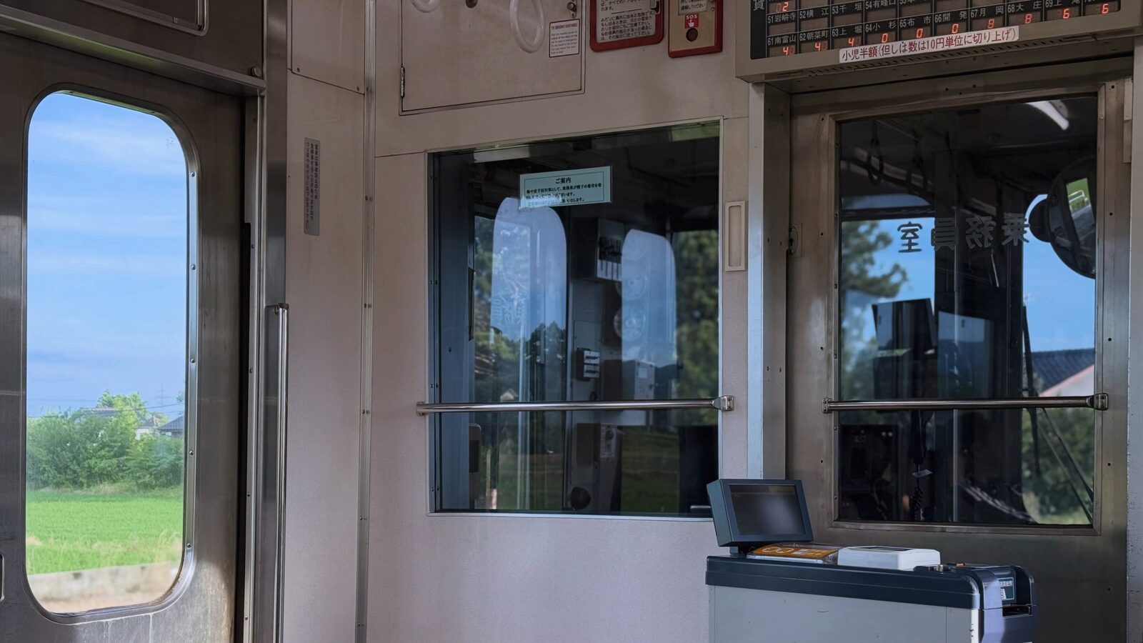 ワンマン電車の運転席と、窓の外の田んぼ