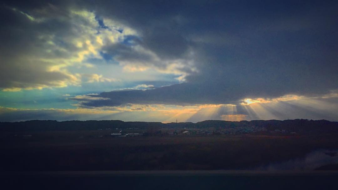 雲のすきまから光がさす、夕方の野