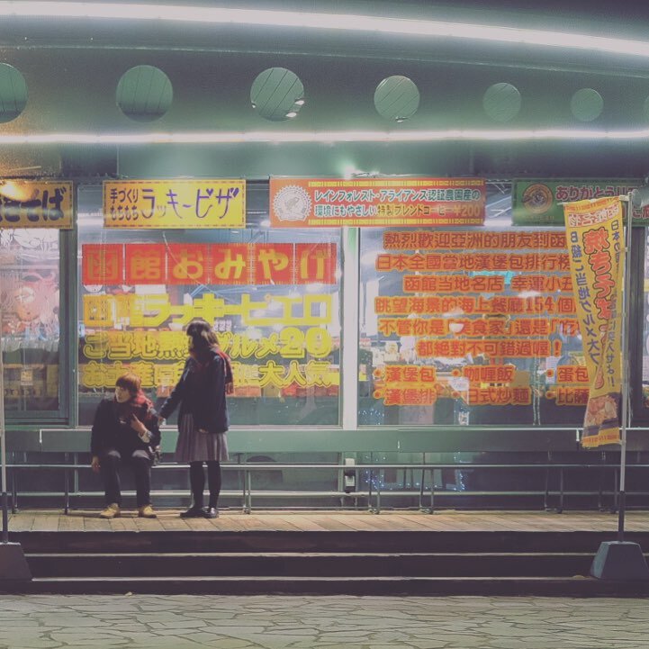 赤い看板のおみやげ屋の前の二人