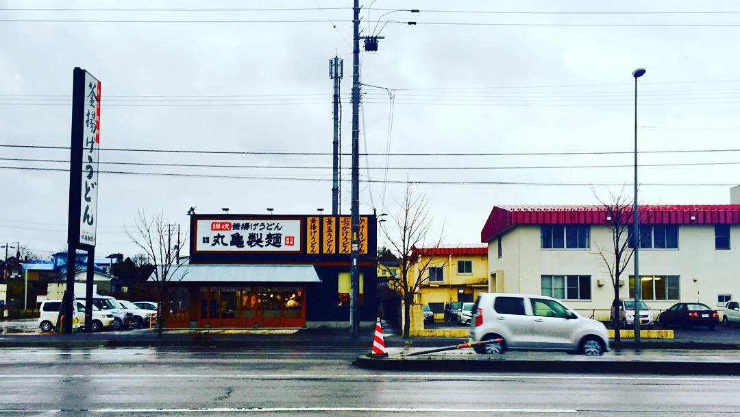 雨の道路の向こうのうどん屋