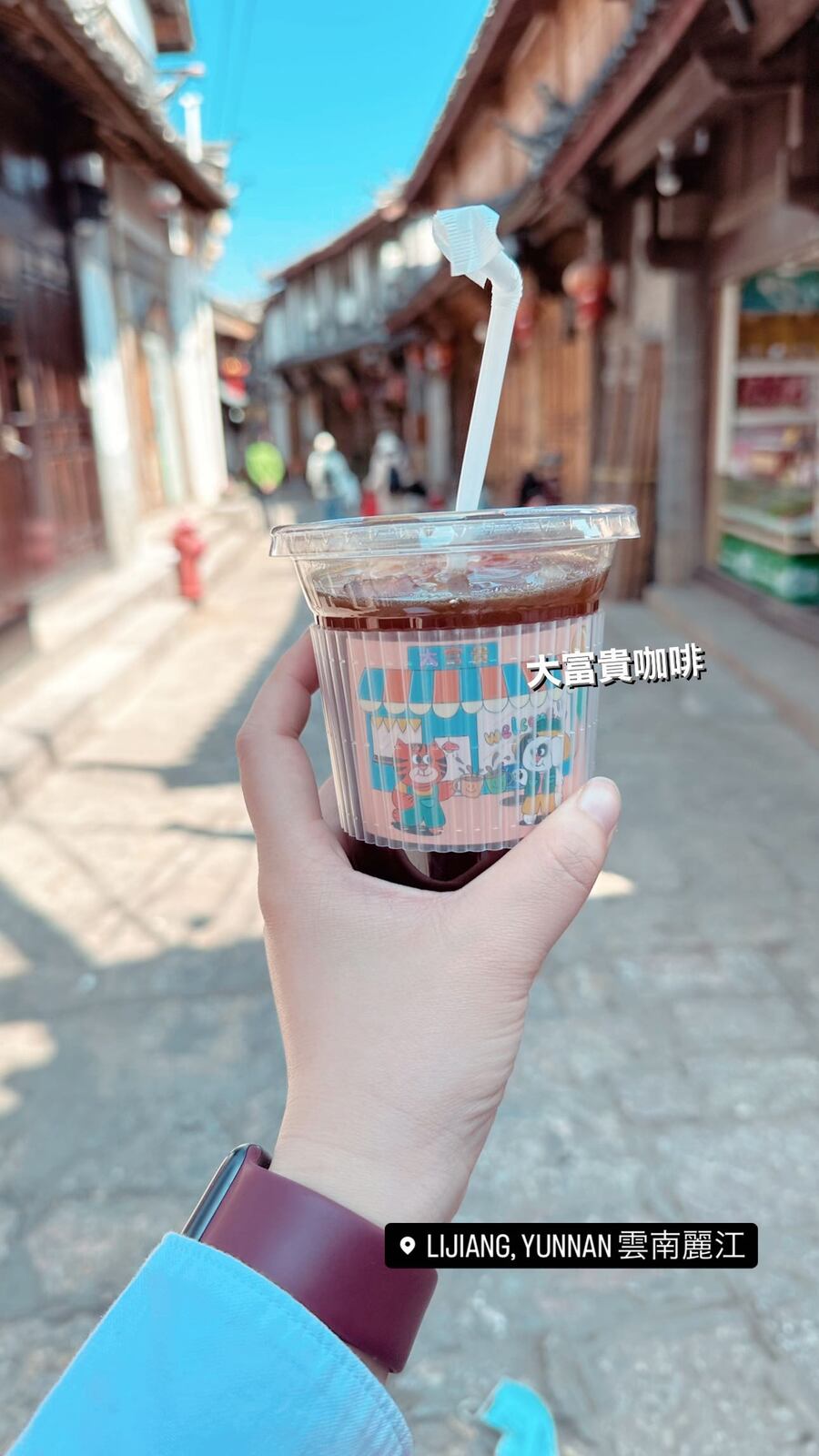 古城の通りで持つ、アイスコーヒーのカップ